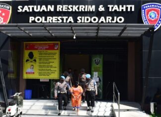 Pelaku E (35), saat digelandang petugas yang merupakan mucikari terhadap putri kandungnya